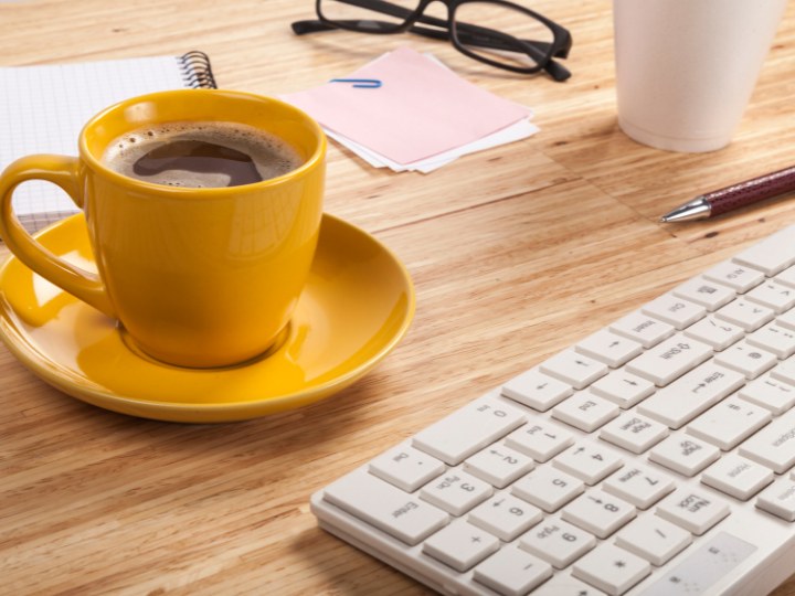Photo of office desk with a cup of Beach Bros Coffee that wholesale bought our coffee beans for the office